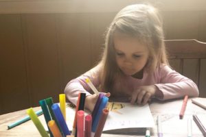 little girl coloring while her mom works