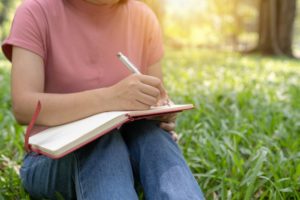 girl writing poetry in the grass